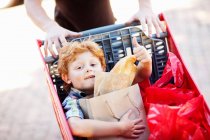 Boy riding in shopping cart — Stock Photo