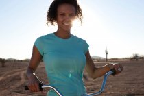 Woman with bicycle in desert landscape — Stock Photo