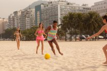 Молодой человек и женщины играют в футбол на пляже Копакабана, Рио-де-Жанейро, Бразилия — стоковое фото