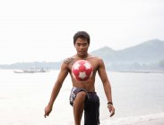Kerl spielt Fußball am Strand — Stockfoto