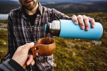 Hiker pouring coffee to cup for friend — Stock Photo