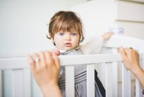 Portrait of female toddler staring from crib — Stock Photo