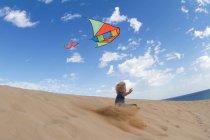 Garçon cerf-volant volant sur une dune de sable — Photo de stock