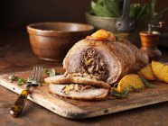 Pato deshuesado con cerdo, naranjas y tenedor sobre tabla de madera - foto de stock