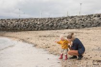 Mère et tout-petit à la plage de sable fin — Photo de stock