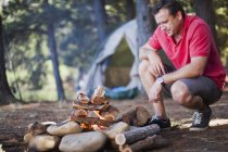 Man starting a fire at campsite — Stock Photo