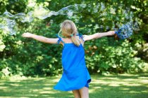 Visão traseira da menina brincando com bolhas no quintal — Fotografia de Stock