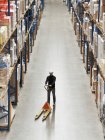 Worker operating dolly in warehouse — Stock Photo