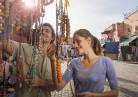 Young couple at market looking at beads, Jemaa el-Fnaa Square, Marrakesh, Morocco — Stock Photo