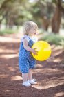 Маленькая девочка с мячом на грунтовой дороге — стоковое фото