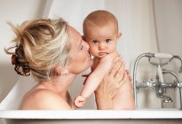Sonriente madre bañándose con el bebé, se centran en primer plano - foto de stock