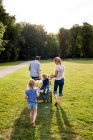 Visão traseira dos pais e três meninas passeando no parque — Fotografia de Stock