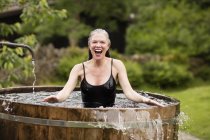 Mature woman standing in fresh cold water tub at eco retreat — Stock Photo