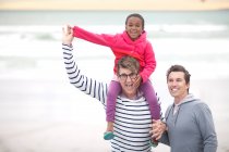 Гей пара гуляє на пляжі з дитиною на плечах — стокове фото