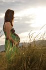 Беременная женщина стоит в поле — стоковое фото