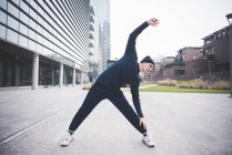 Young male runner stretching in city — Stock Photo