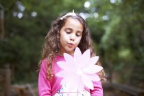 Girl blowing flower pinwheel at garden birthday party — Stock Photo