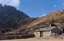 Stone house in dusty mountain valley under blue sky — Stock Photo