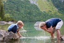 Rapaz a lavar a cara num lago imóvel — Fotografia de Stock