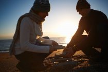 Coppia matura accatastamento pietre sulla spiaggia al tramonto — Foto stock