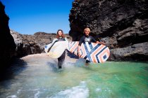 Paar läuft mit Surfbrettern im Wasser — Stockfoto