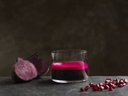 Purple raw beetroot and apple juice, halved beetroot and pomegranate seeds — Stock Photo
