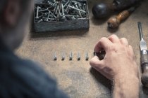 Man arranging screws of similar size in a row — Stock Photo