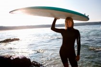 Frau steht mit Surfbrett — Stockfoto