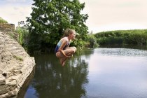 Vista lateral da menina pulando no lago — Fotografia de Stock