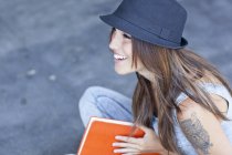 Estudante feminina usando chapéu livro segurando — Fotografia de Stock