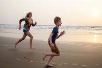 Mutter und Sohn rennen am Strand — Stockfoto