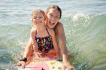 Mother and daughter boarding in ocean — Stock Photo