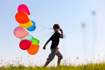 Хлопчик з різнокольоровими кульками в траві — стокове фото