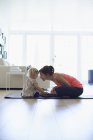 Mãe adulta média e filha criança praticando posição de lótus na sala de estar — Fotografia de Stock