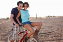 Couple on bicycle in desert landscape — Stock Photo