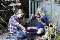 Две девушки в саду сажают семена в горшки — стоковое фото