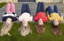 Four teenage girls lying on patio and looking back — Stock Photo