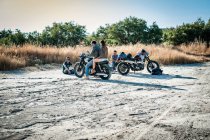 Four motorcycling friends taking a break on arid plain, Cagliari, Sardinia, Italy — Stock Photo