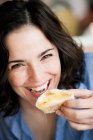 Woman eating bread with honey and smiling at camera — Stock Photo