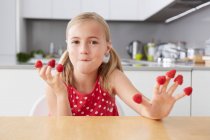 Chica comiendo frambuesas de los dedos - foto de stock