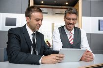 Dos hombres de negocios mirando la tableta digital - foto de stock