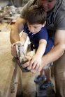Father mentoring son on carpentry in boat workshop — Stock Photo