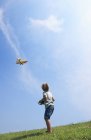 Вид сзади маленького мальчика летящего модели самолета — стоковое фото