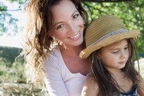 Ritratto di donna matura e figlia con cappello di paglia nel parco — Foto stock