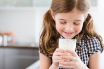 Девушка смотрит в стакан молока — стоковое фото