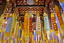 Buddhist temple interior with gold painted flags — Stock Photo