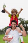 Coach portant enfant avec trophée — Photo de stock