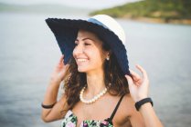 Жінка біля моря, капелюсі — стокове фото