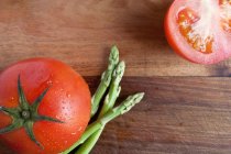 Tomatoes and asparagus on wooden surface — Stock Photo
