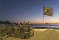 Castillo de arena y bandera brasileña en la playa de Copacabana, Río de Janeiro, Brasil - foto de stock